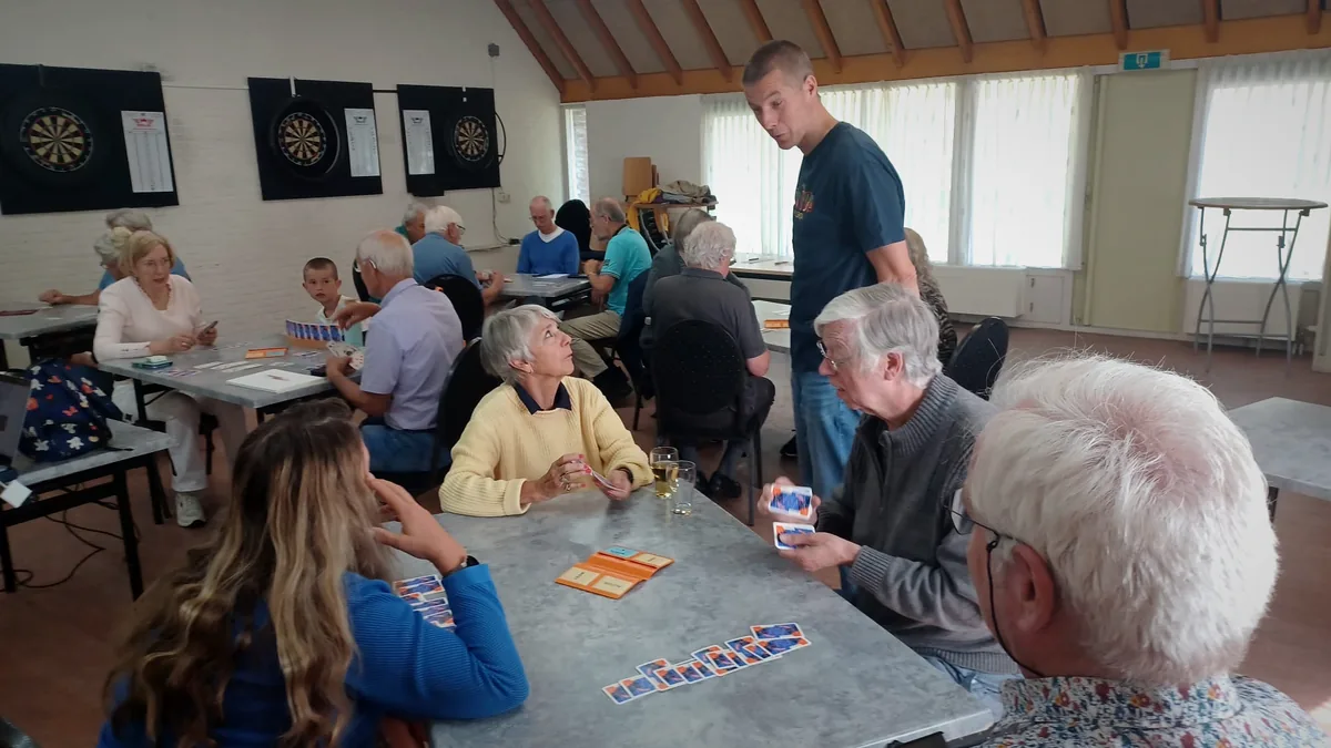 Bridgespelers oefenen aan tafel tijdens clinic met begeleiding