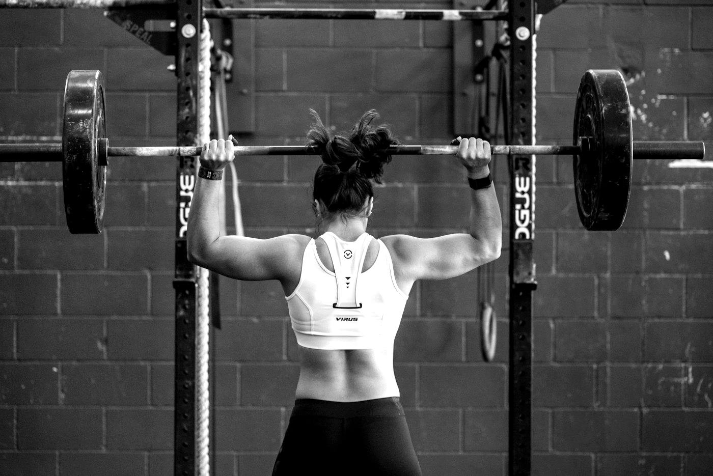Athlete gripping a barbell at a rack, ready to press
