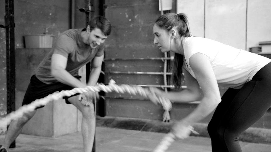 Two athletes working battle ropes together