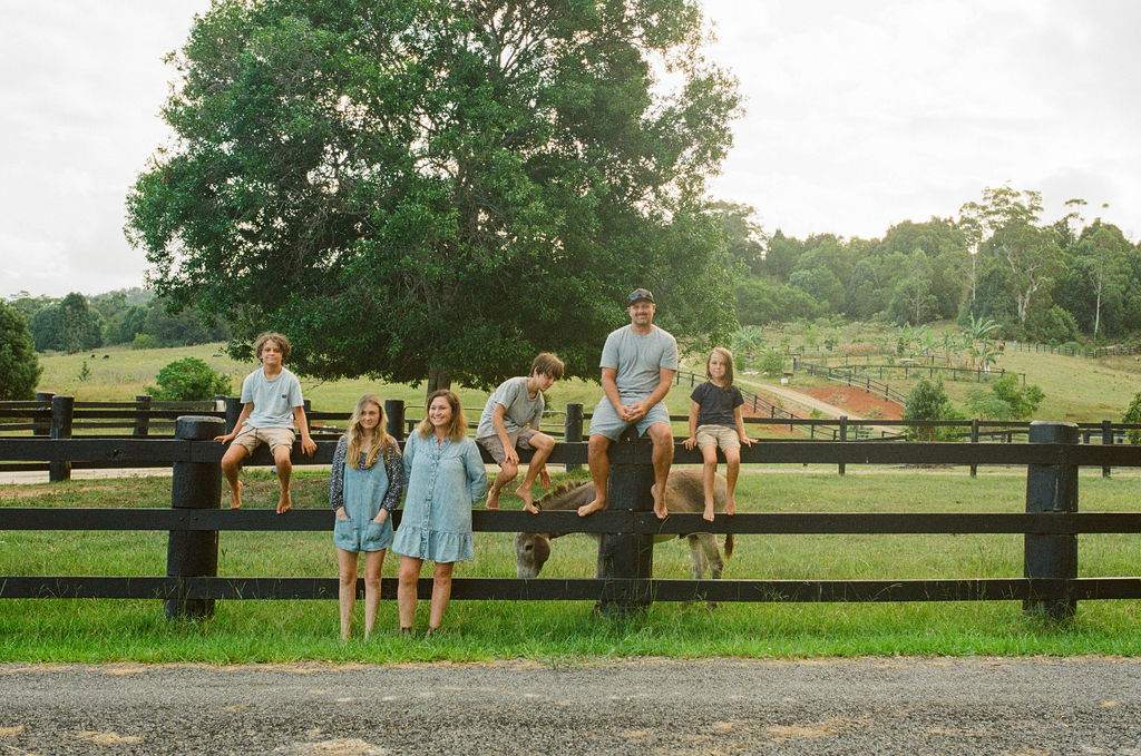 The Stefanac family sitting along the fence rail on their farm in Northern NSW