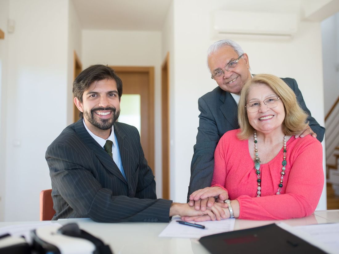 Happy senior couple with their insurance agent after reviewing life insurance paperwork