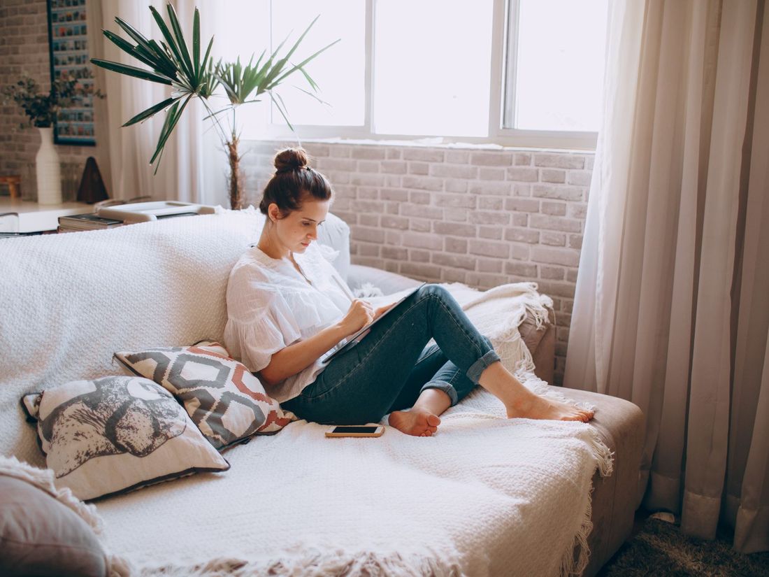 Woman relaxing on her sofa while comparing individual health insurance plans on a tablet