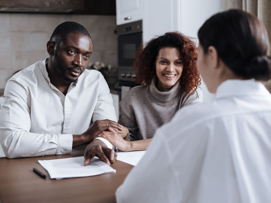 Smiling couple meeting with an insurance advisor at their kitchen table to compare coverage options