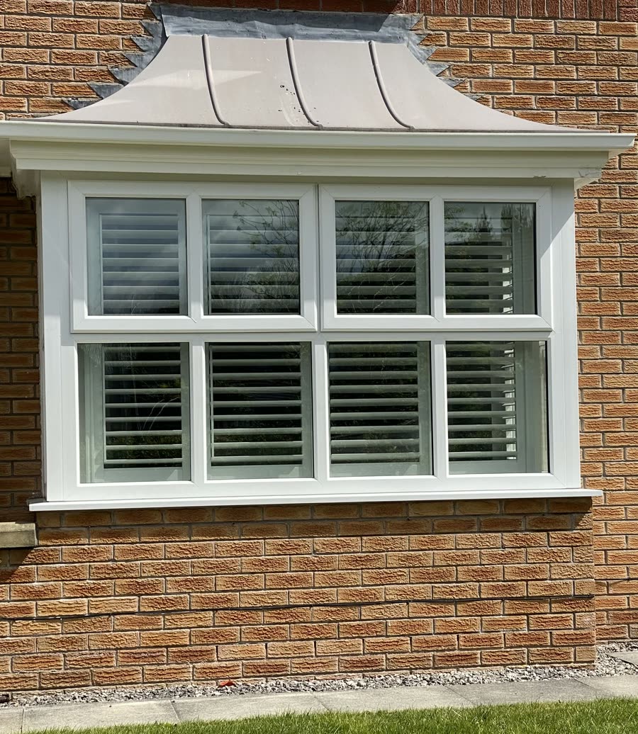 Plantation shutters seen from outside a brick bay window