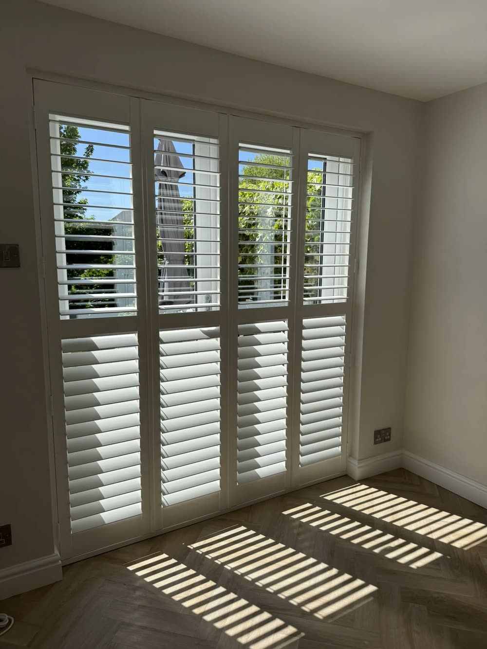 Full-height polyvinyl plantation shutters in a living room in Astley