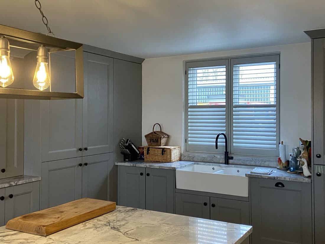 Plantation shutters above a Belfast sink in a shaker kitchen