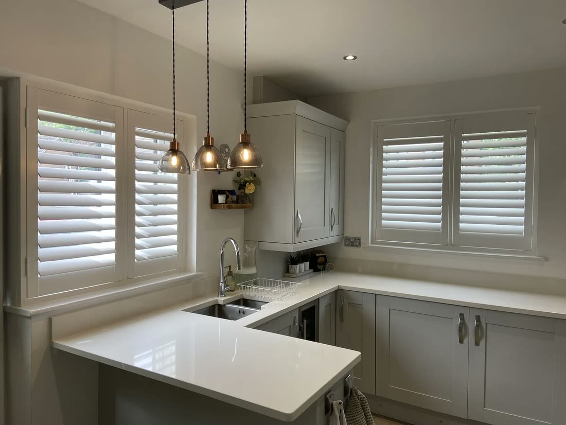 Plantation shutters on two windows of a modern corner kitchen