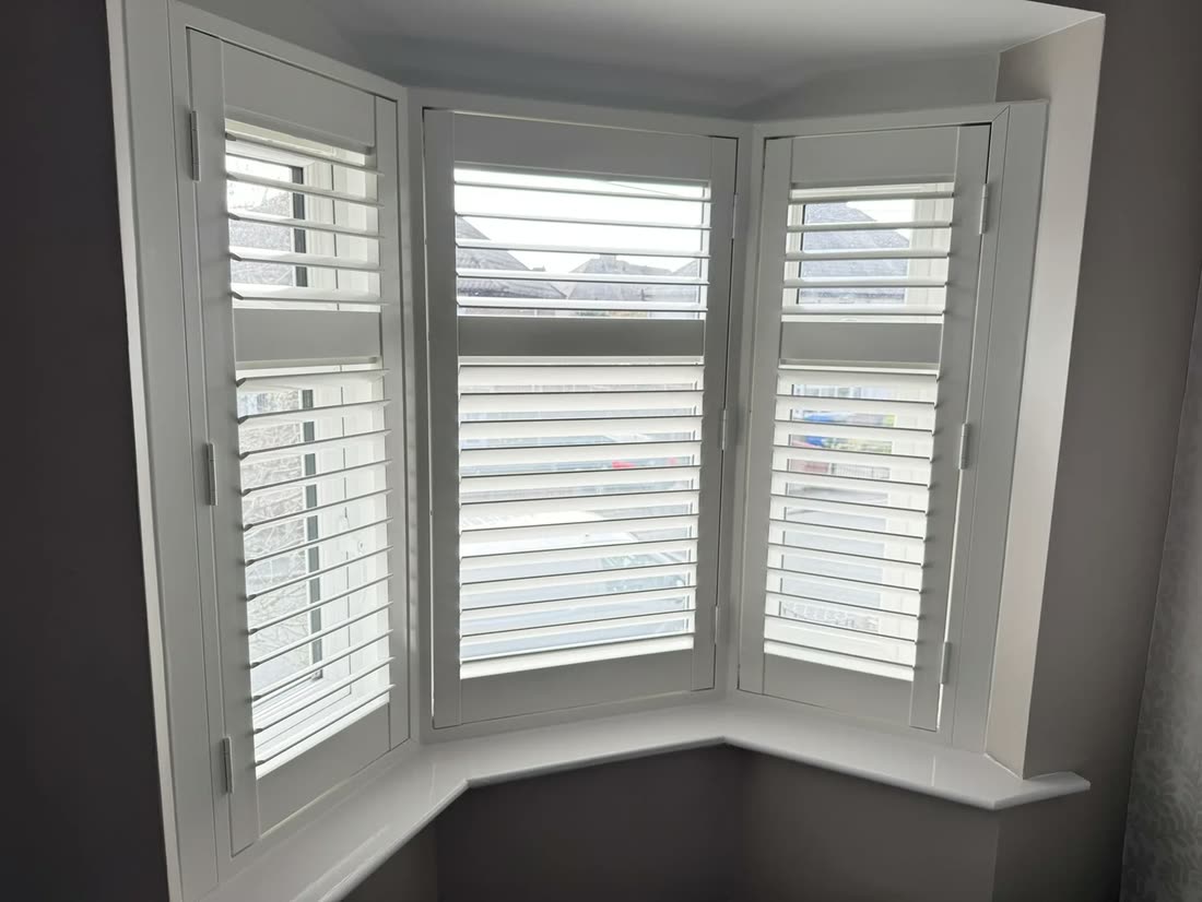 Plantation shutters fitted panel by panel around an angled bay window
