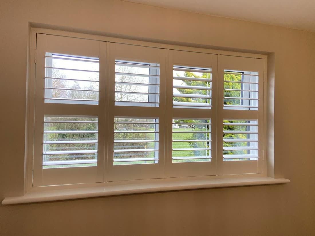 A wide window fitted with eight plantation shutter panels
