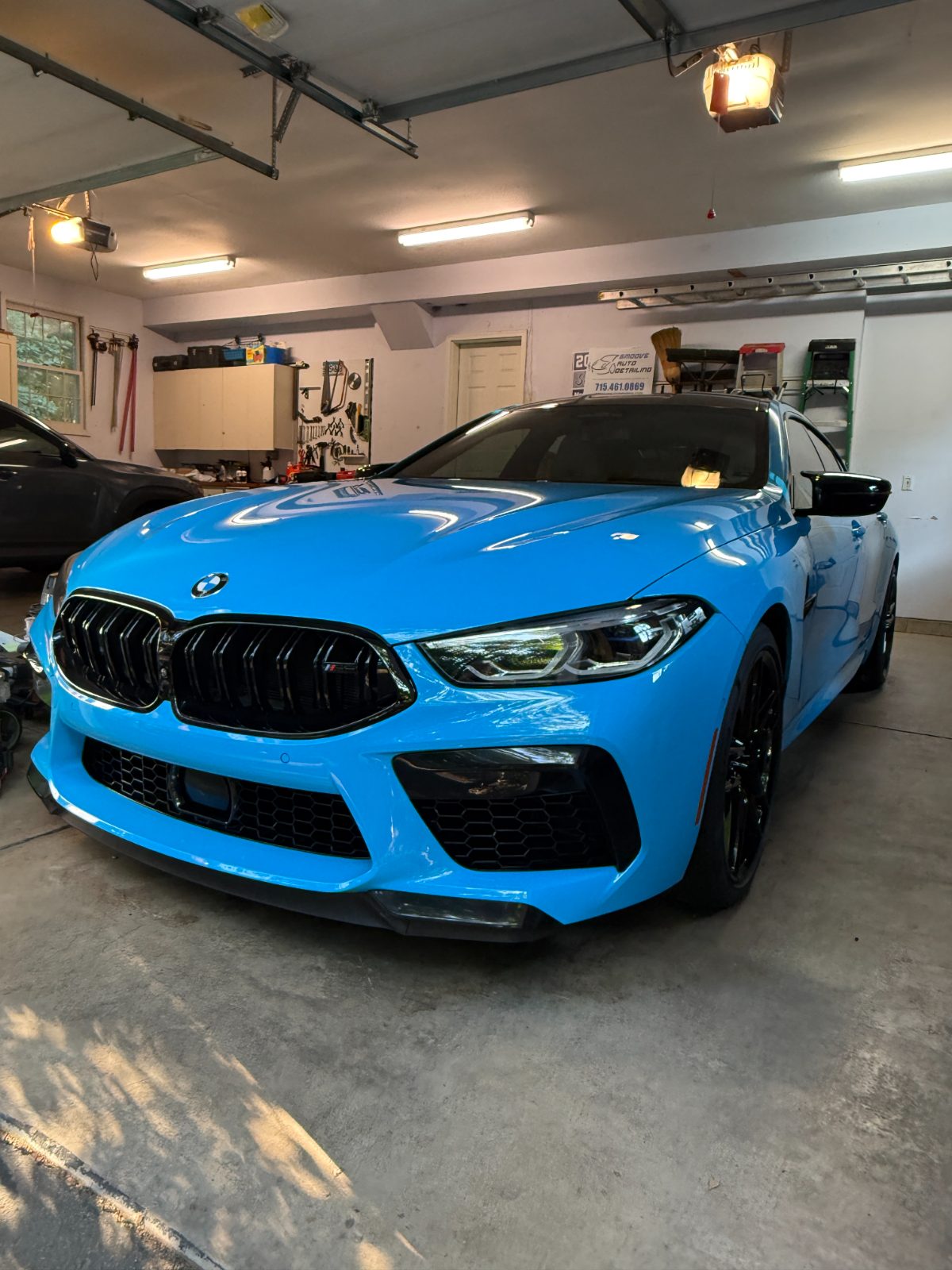 Freshly detailed blue BMW M8 in the garage bay — mobile car detailing Eau Claire