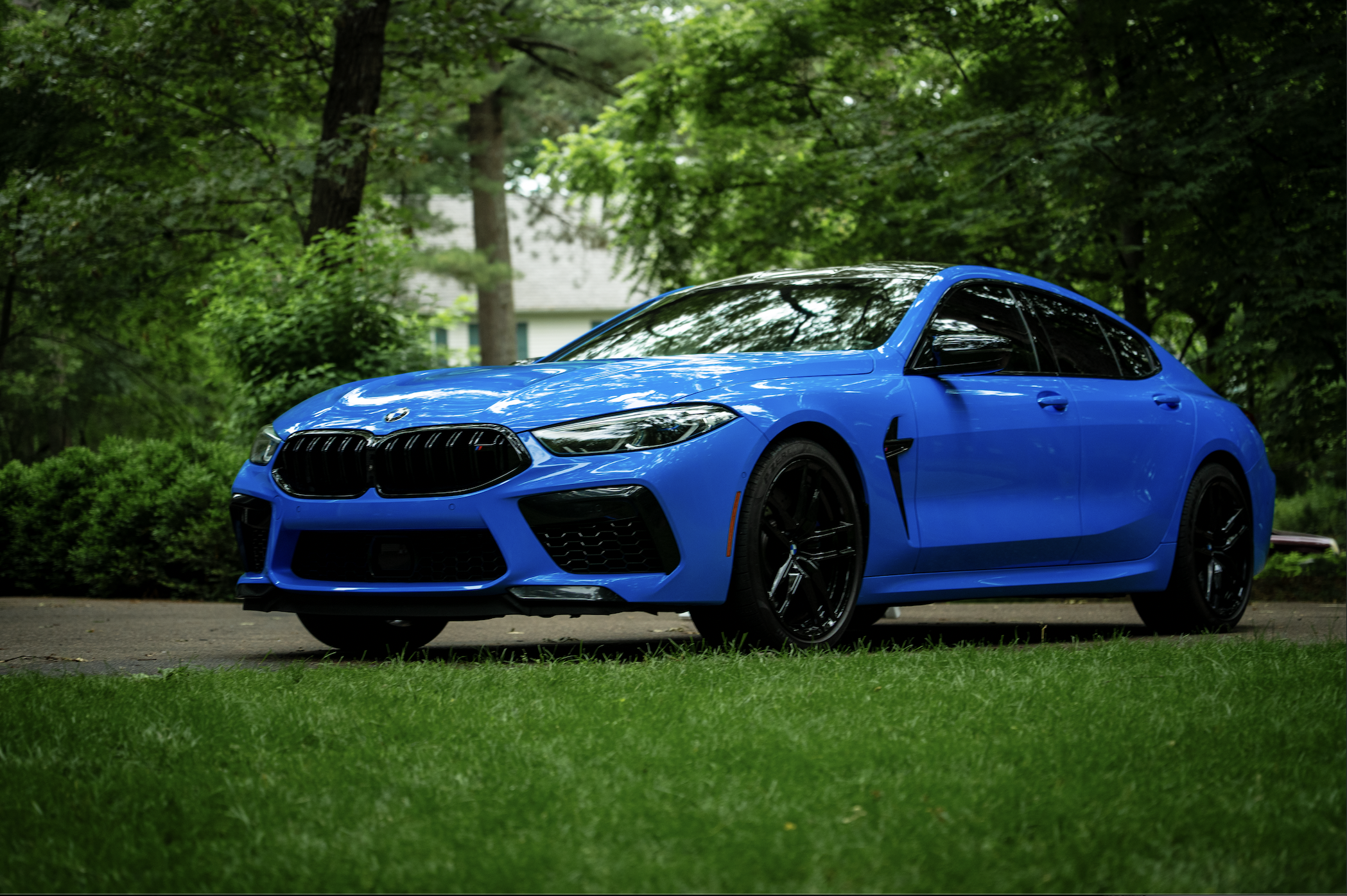 Riviera blue BMW M8 with a fresh Smoove ceramic coating in a tree-lined Eau Claire driveway