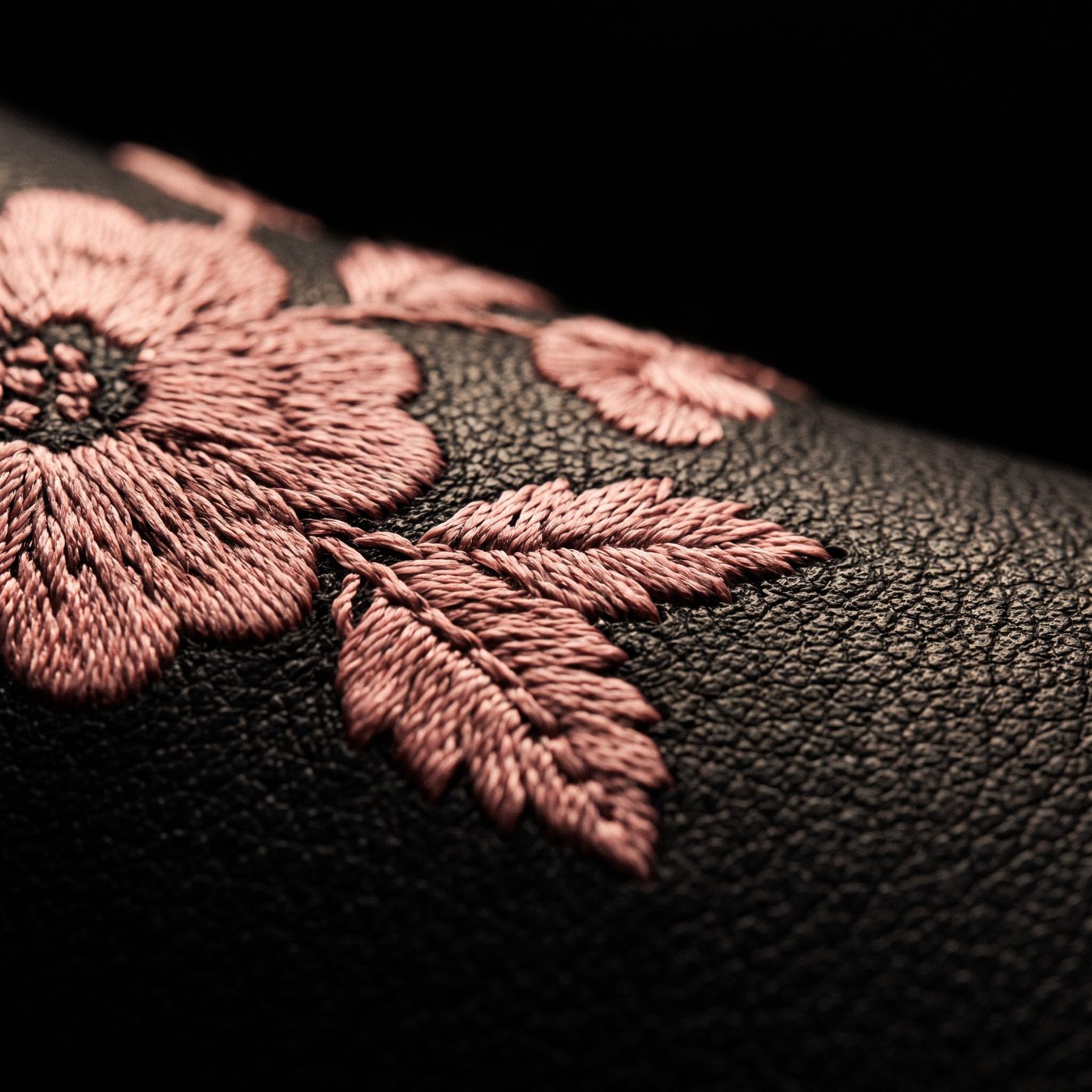 Detalle macro del bordado rosa viejo sobre piel negra