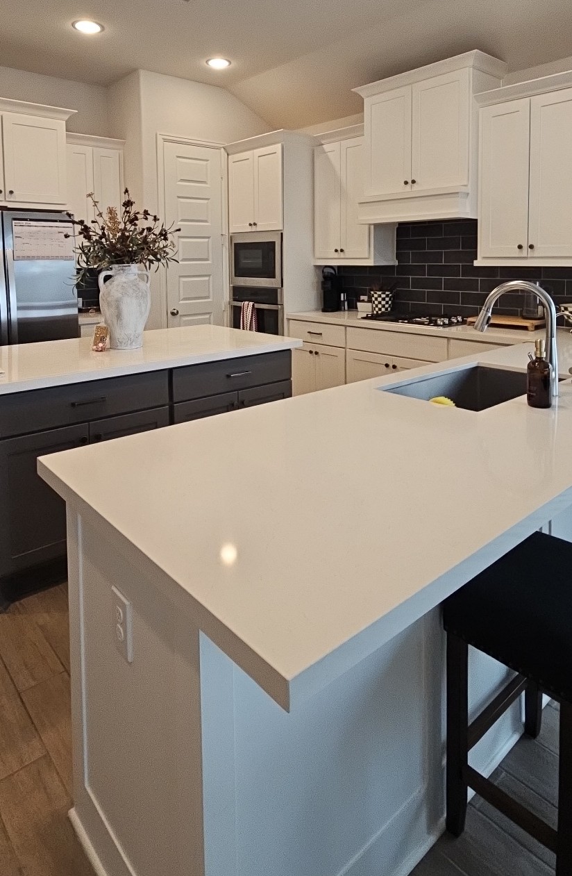Kitchen with white countertops, white cabinets, and a black tile backsplash