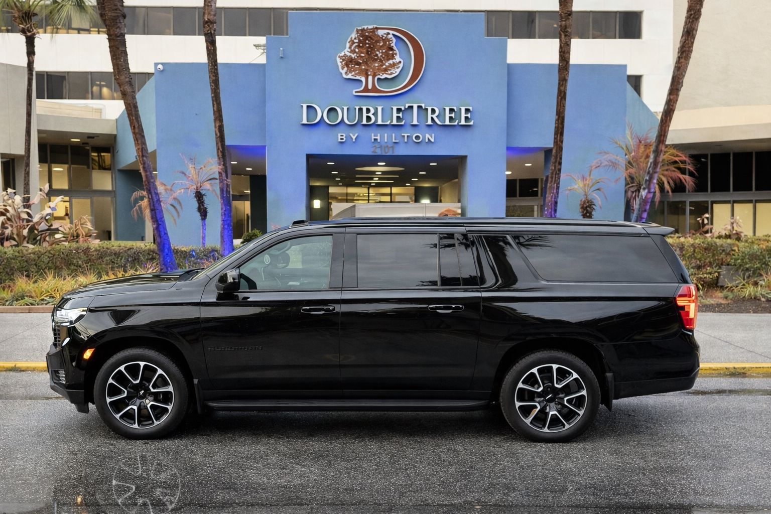 Professional chauffeur standing next to luxury SUV in Jacksonville
