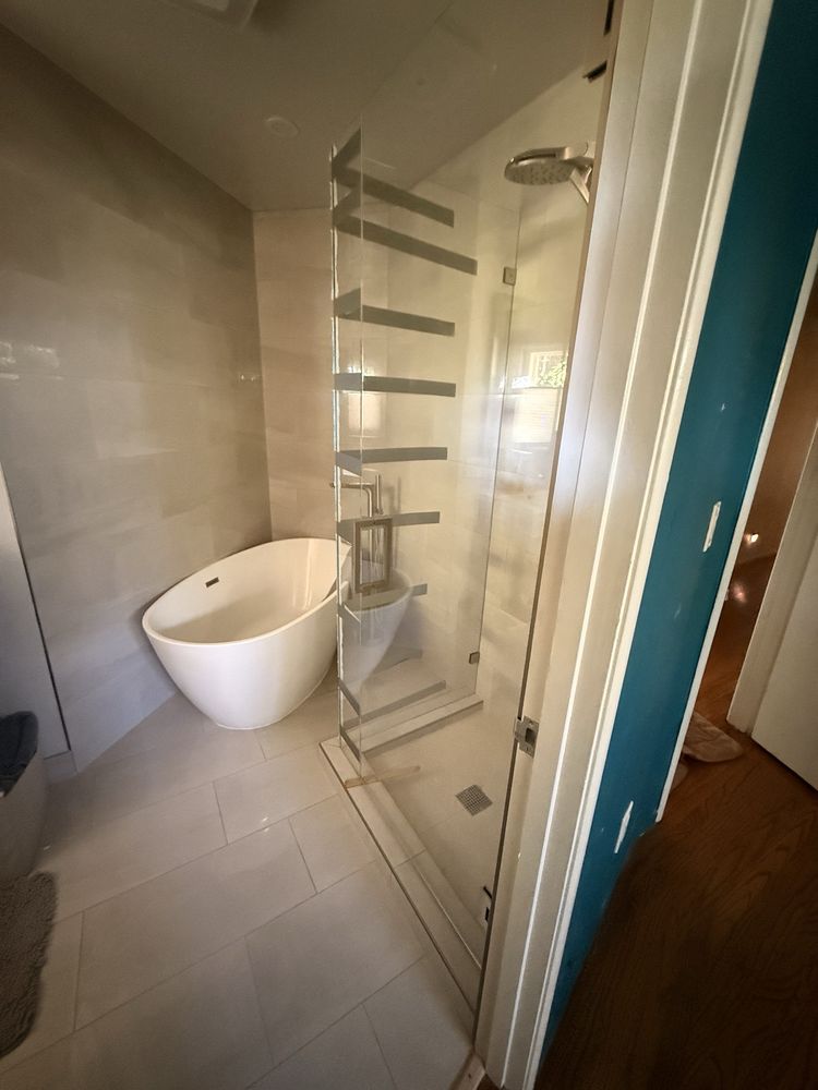 Frameless glass shower enclosure next to a freestanding tub