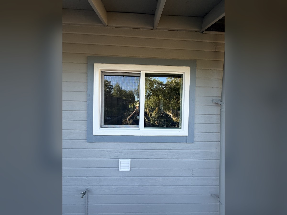 White sliding window installed in gray siding
