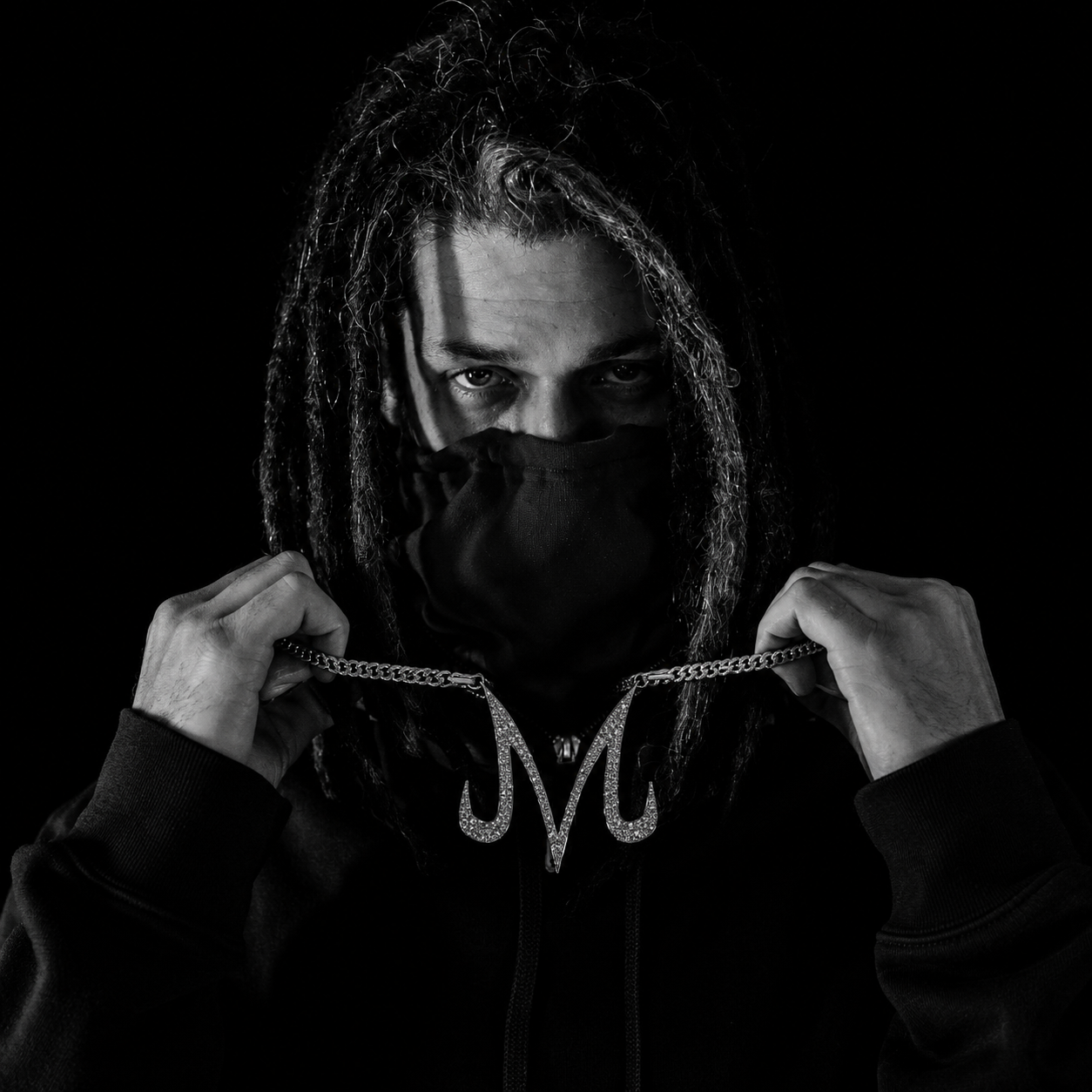 Black and white portrait of Mouse holding up his M chain