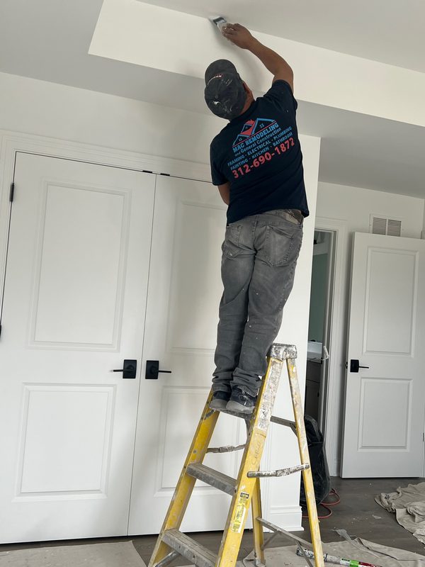 Worker on a ladder in a doorway between white paneled doors
