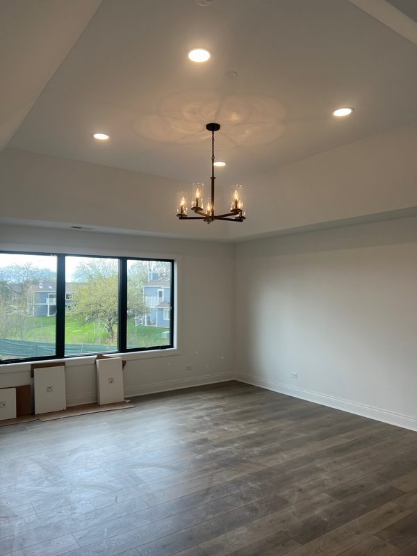 Empty finished room with a chandelier and large black-framed windows