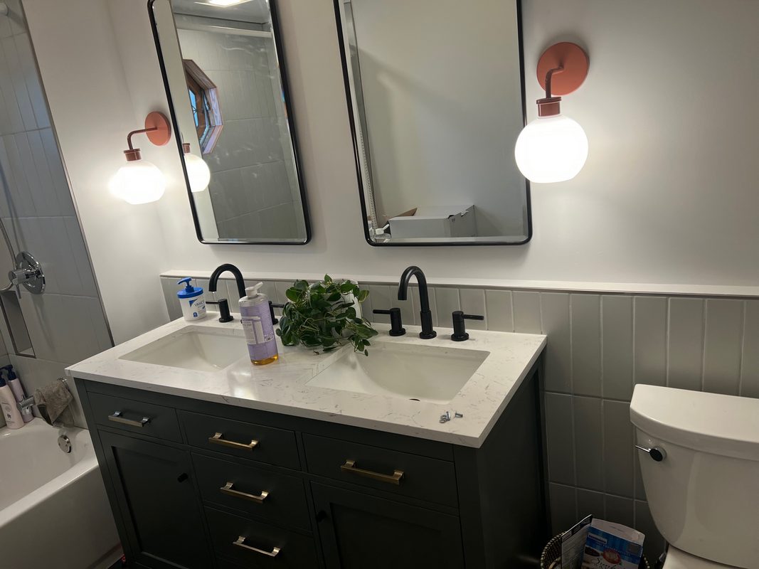 Bathroom vanity with a dark cabinet, a white countertop and two mirrors