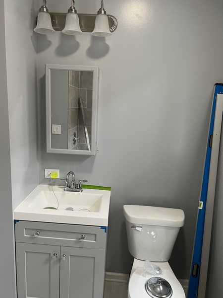 Gray bathroom with a small vanity, a mirror cabinet and a toilet