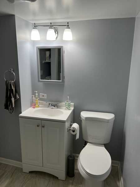 Bathroom with a vanity, a toilet and a wall light fixture