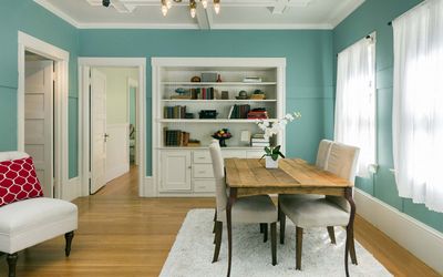 Dining room with teal walls, white built-in shelves and a wood table