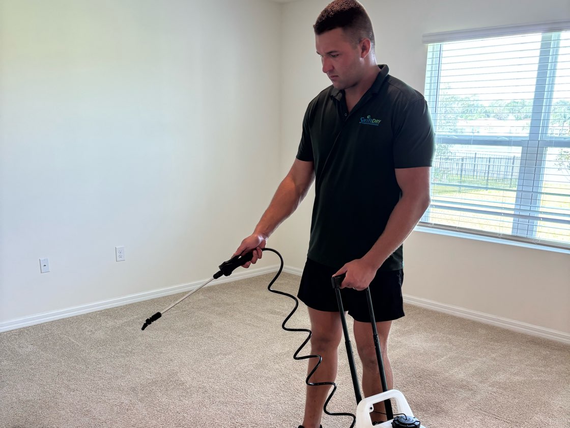 A Swift Dry technician pre-treating a carpet with a pump sprayer before the clean