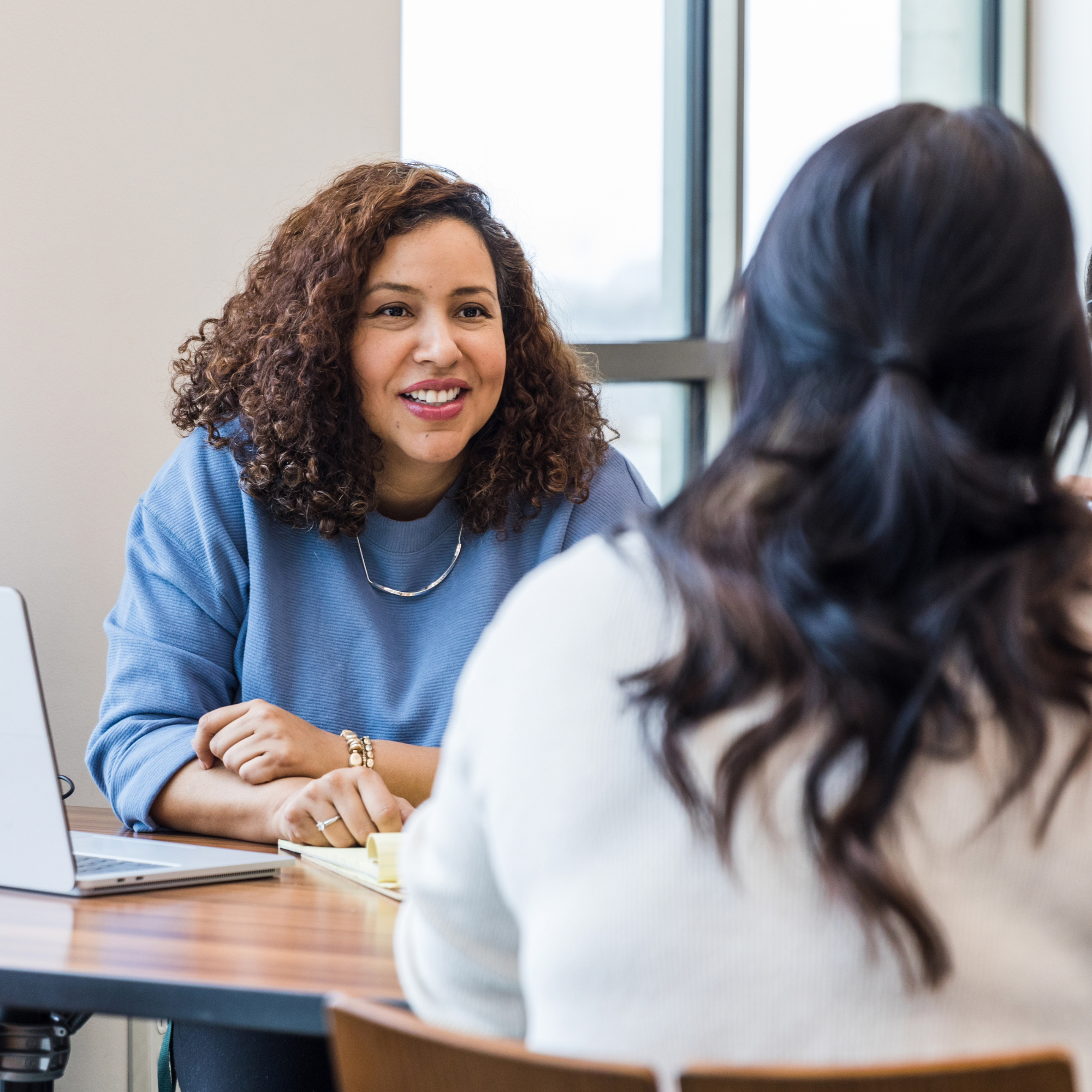 Female CEO in business coaching meeting, smiling, professional discussion at office desk