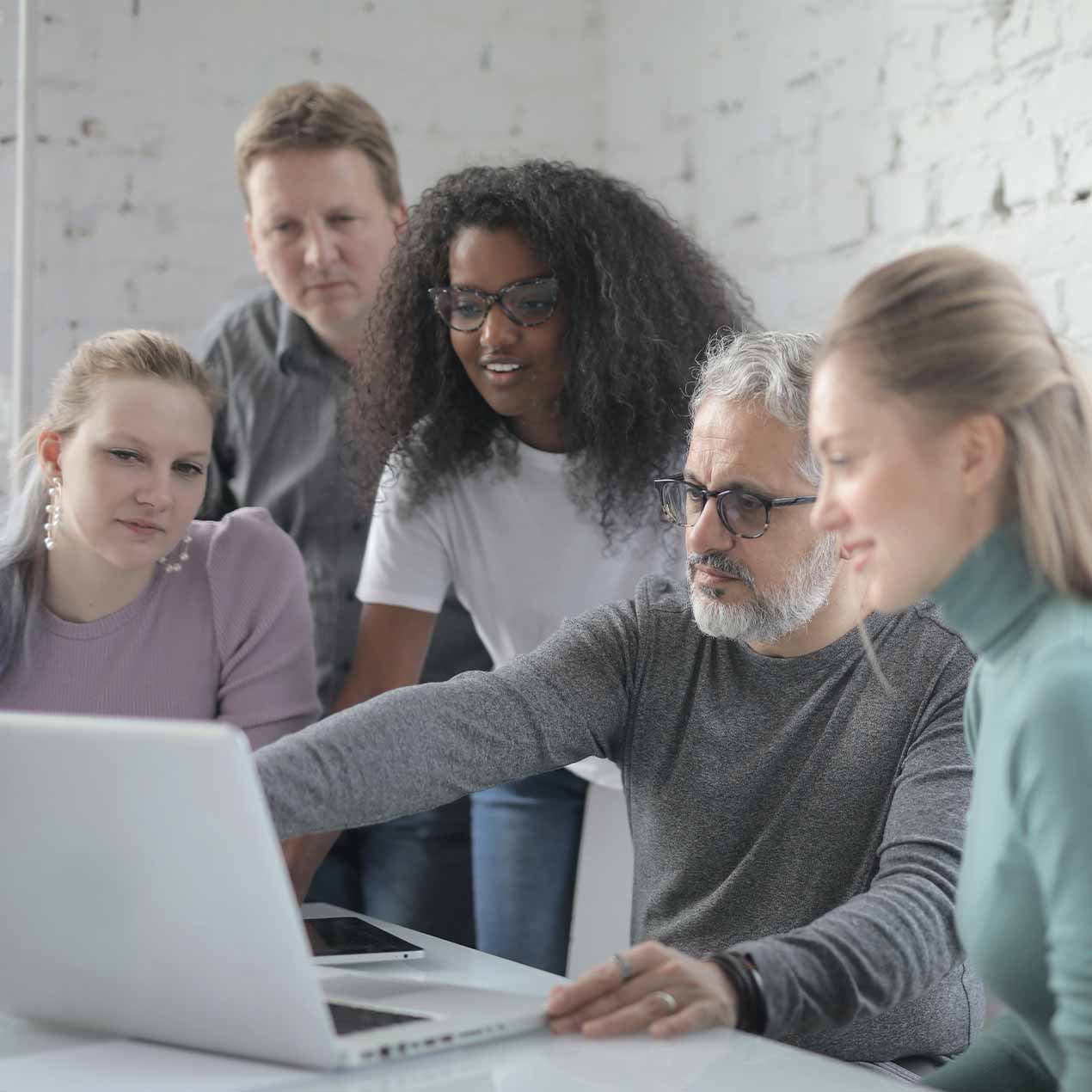Colleagues gathered around a laptop together in a small office