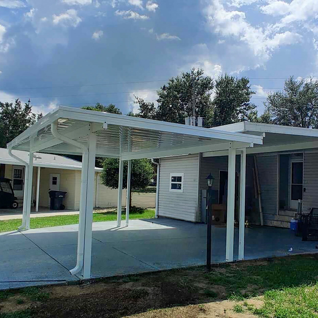 Carport extension adding covered space for a second vehicle
