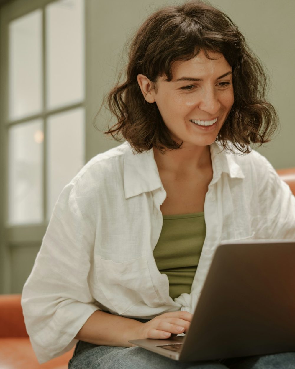 A woman smiling as she talks on a video call from her laptop at home