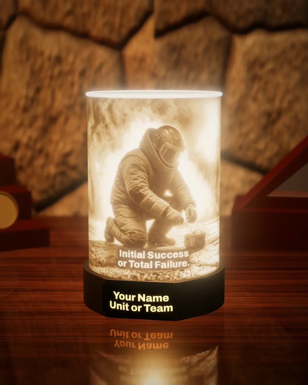 EOD bomb technician tribute lithophane lamp lit warm, showing a bomb technician in a blast suit kneeling over a device, above the glowing words “Initial Success or Total Failure.”, with the black base nameplate glowing “Your Name / Unit or Team”, on a wooden desk against a stone wall