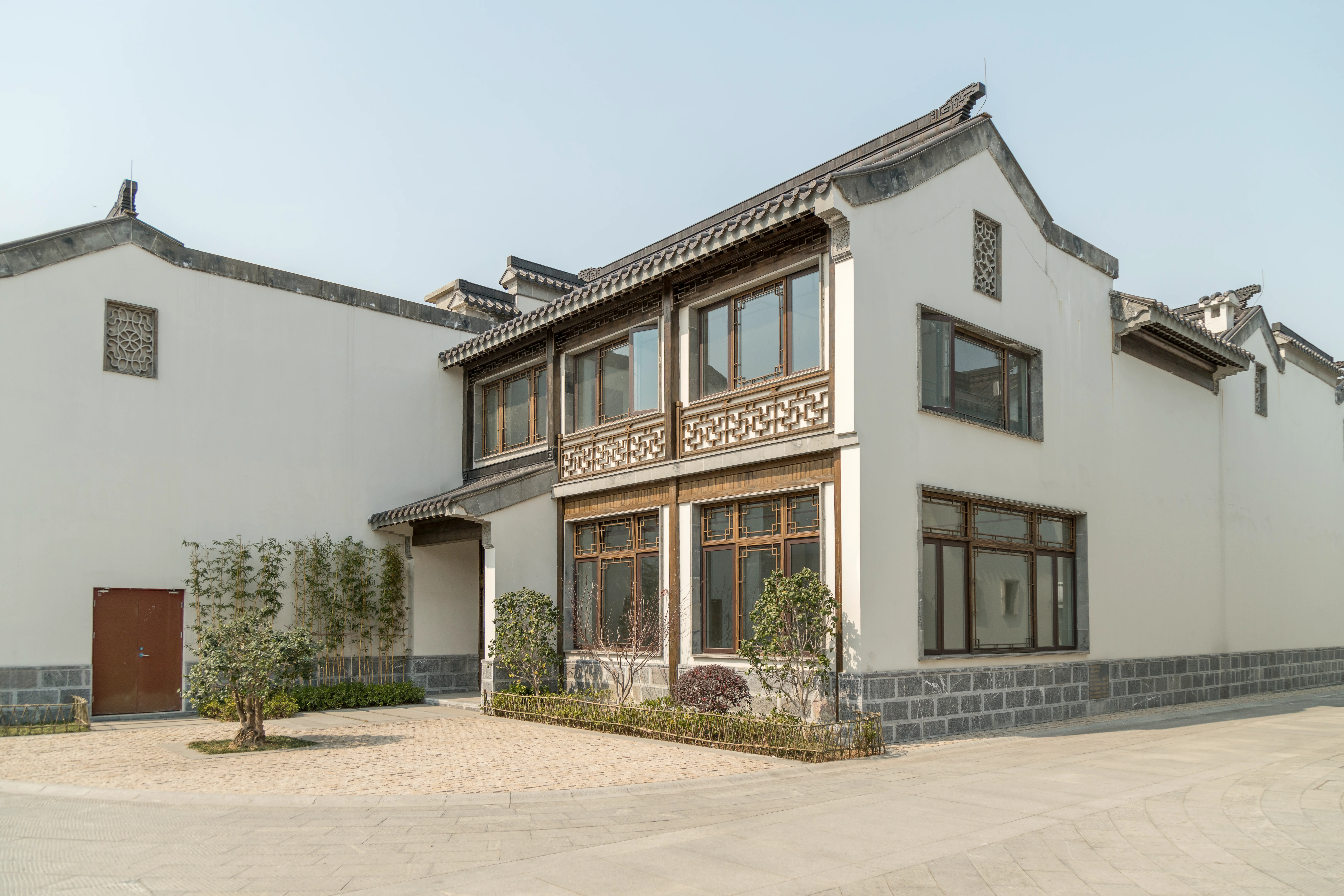 A modern building merging traditional Chinese architectural style with grey roofs, brown-framed windows, and white walls.