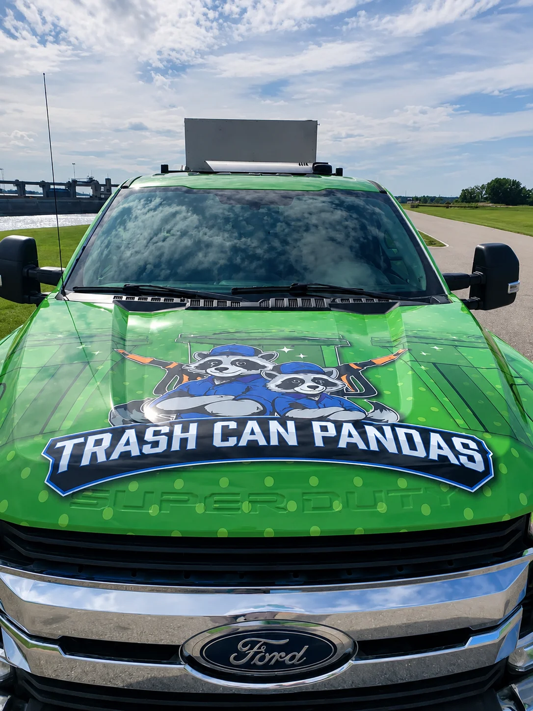 Trash Can Pandas cleaning truck sanitizing residential garbage bins outdoors, featuring raccoon mascot branding and eco-friendly trash can cleaning services.