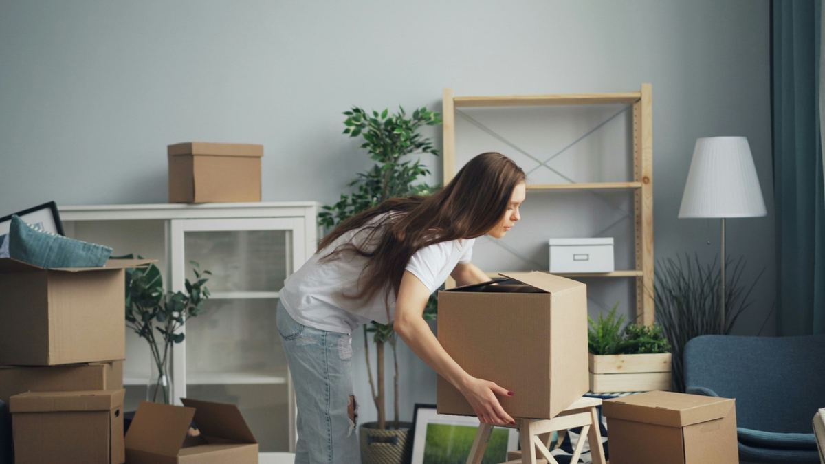 A woman carrying a box into her new living room