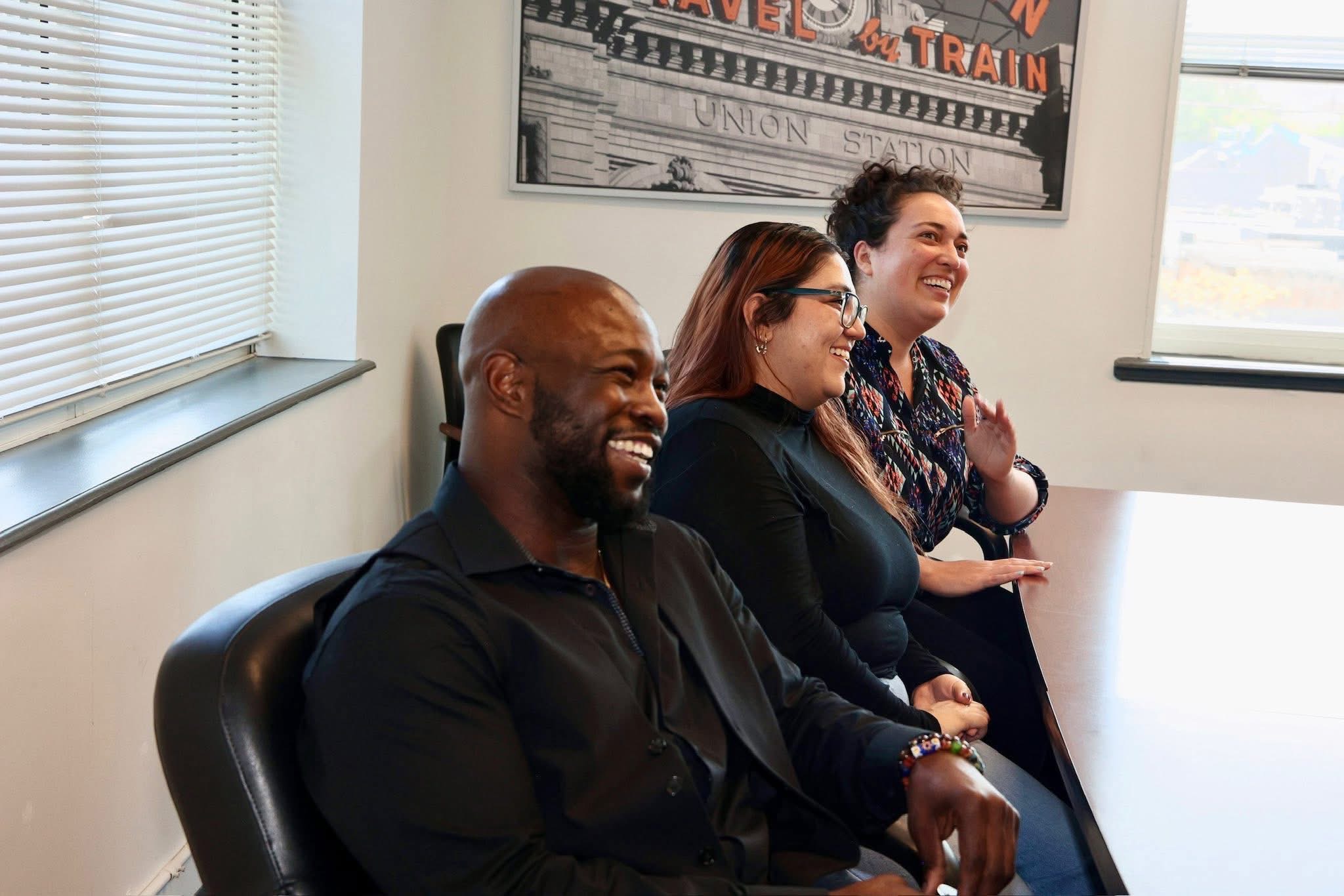 Three people laughing during a meeting in the small conference room