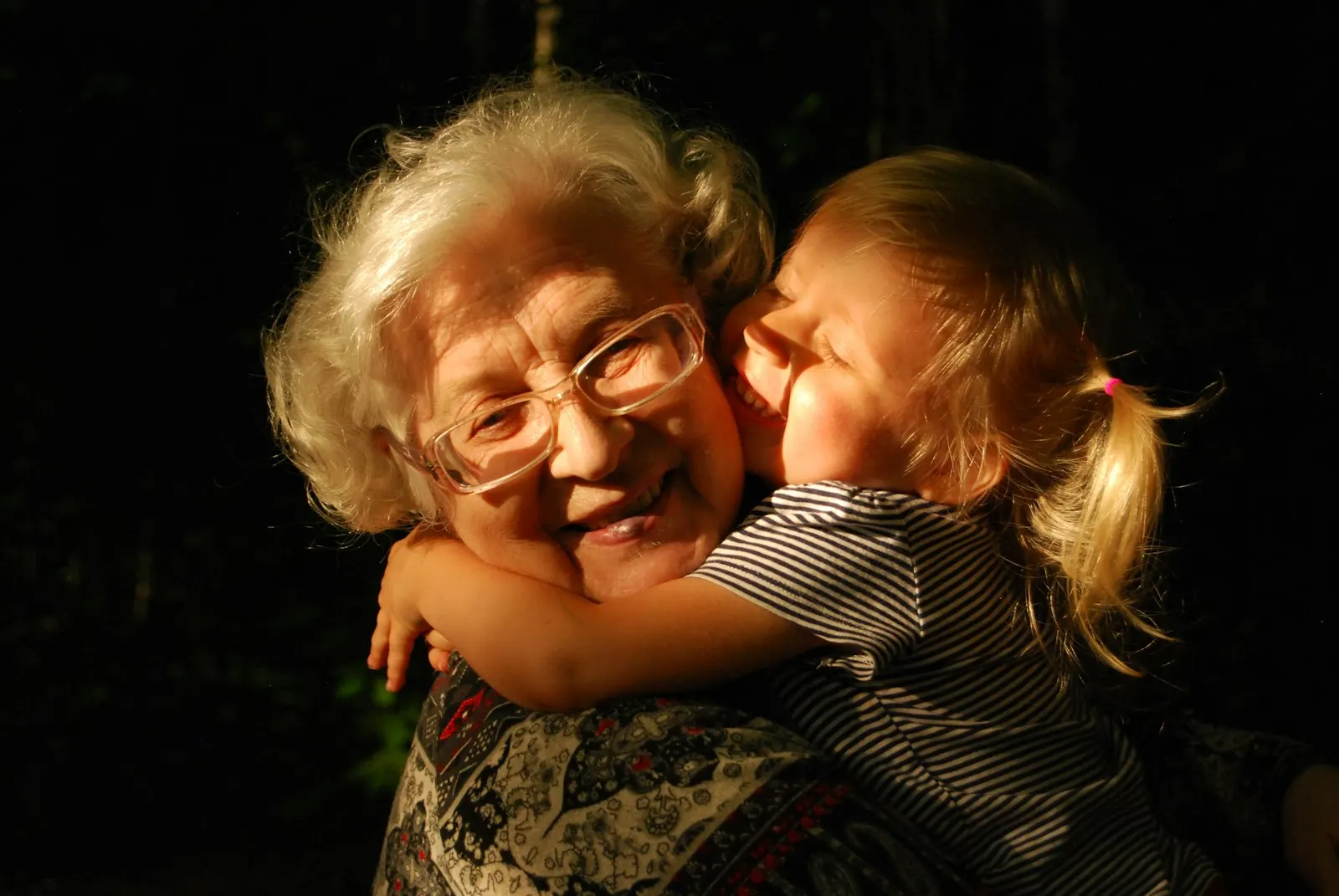 Grandmother smiling as her granddaughter hugs her