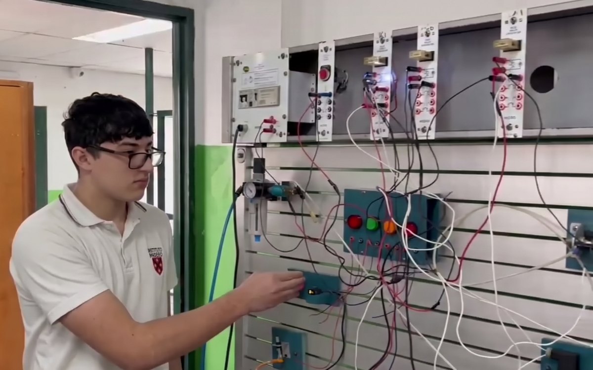 Un alumno de Electromecánica conecta un sensor en el tablero de electroneumática