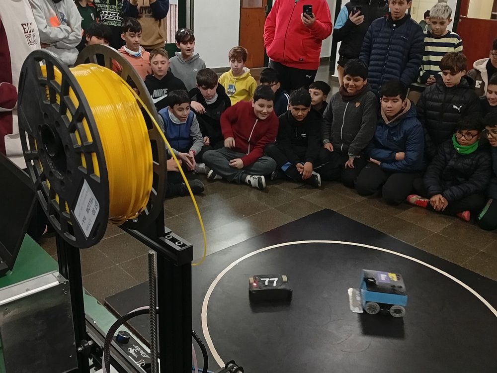 Chicos de los Talleres Tecnológicos mirando robots de sumo y una impresora 3D