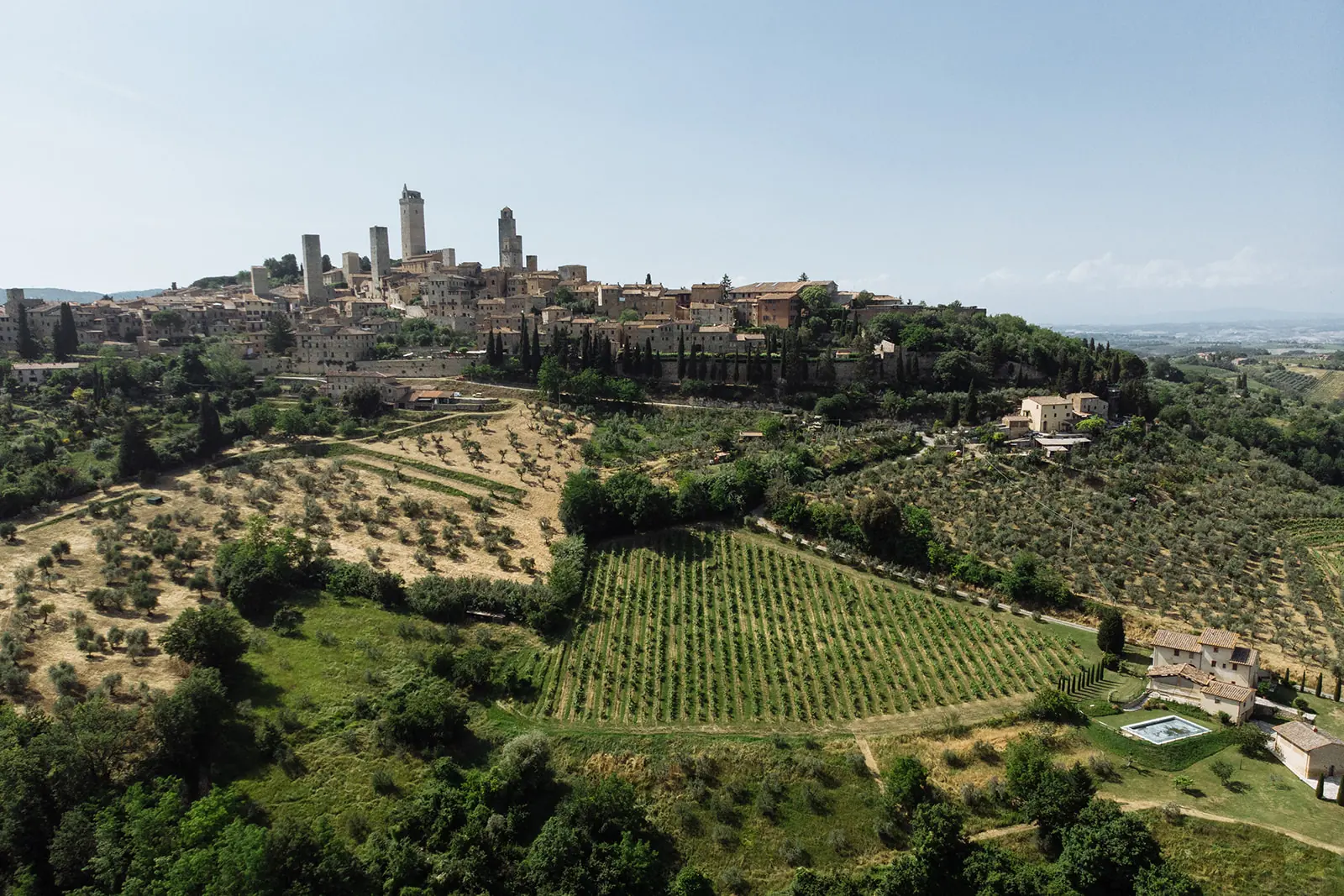 Stone courtyard of a Tuscan castle set for an intimate wedding dinner, with hills behind