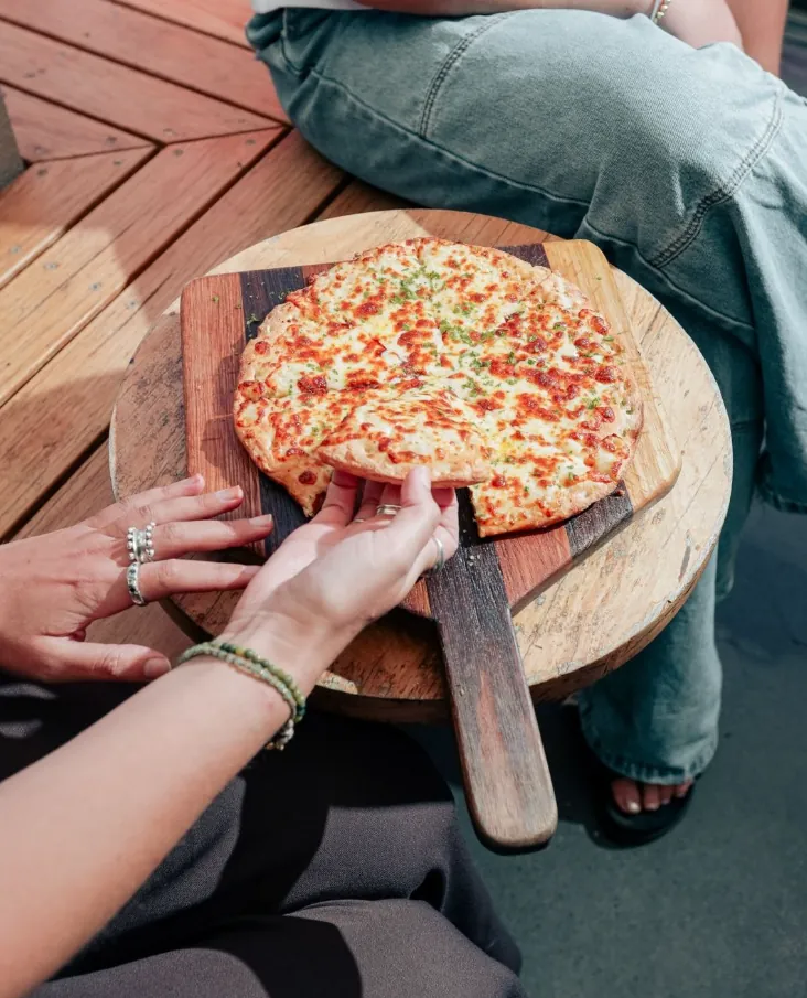 Cheesy garlic pizza on a paddle board in the beer garden