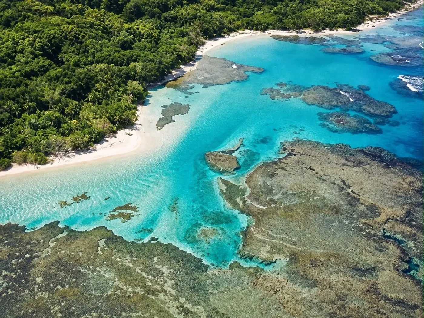 Aerial view of a sheltered turquoise cove and natural reef