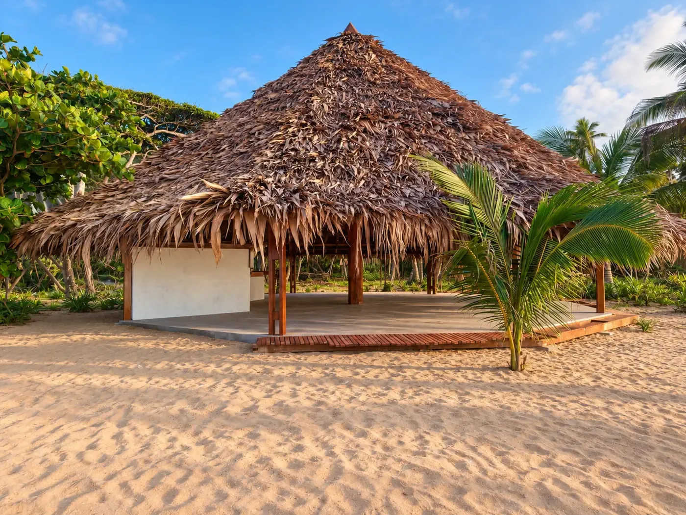 The palm-thatched beachfront gazebo and timber terrace on the sand