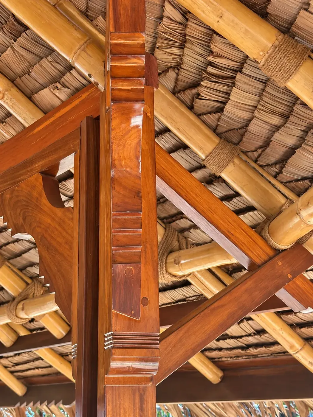 Detail of a carved wooden post and bamboo roof structure