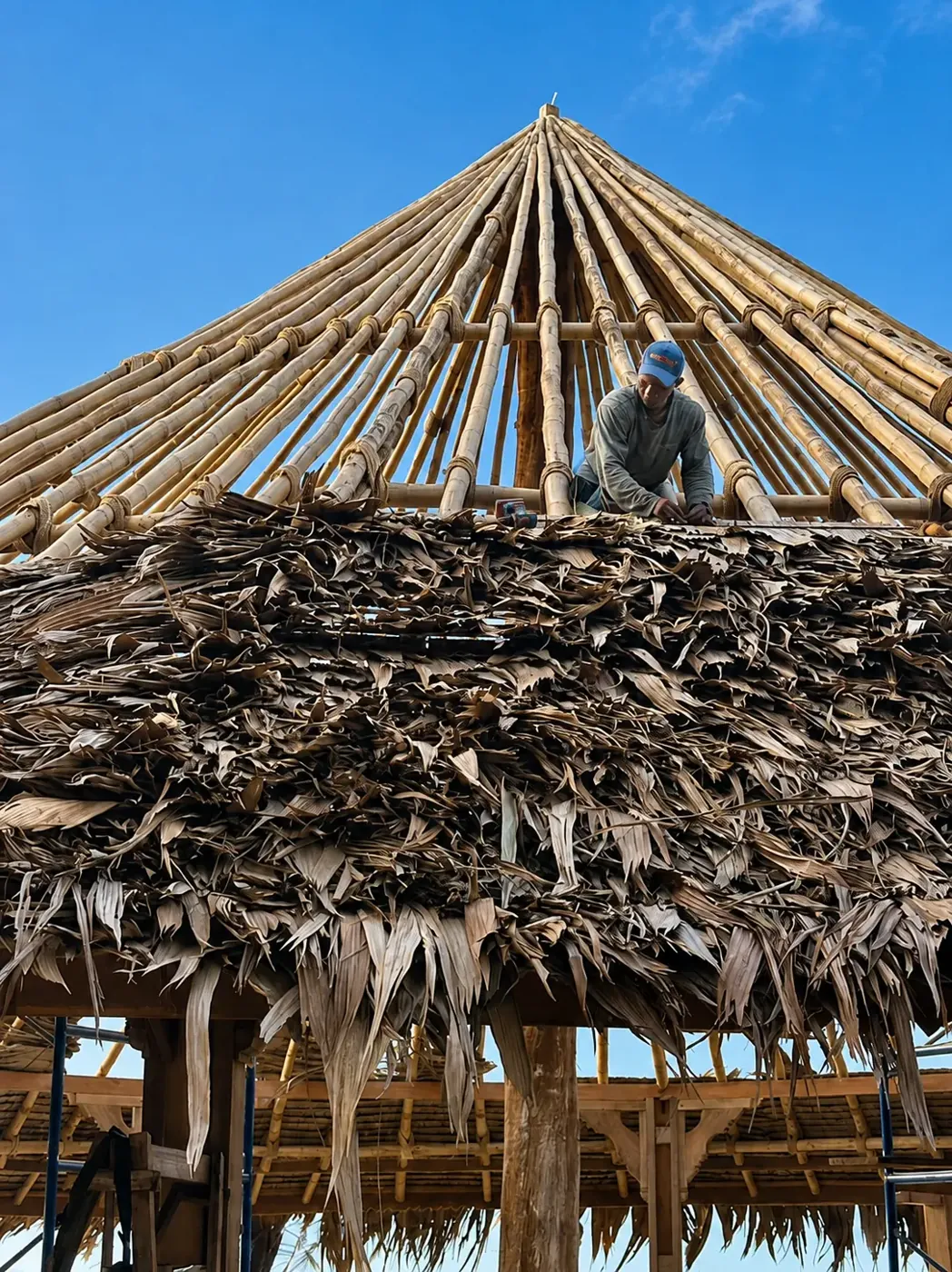 Artisan installing natural thatch on the gazebo roof
