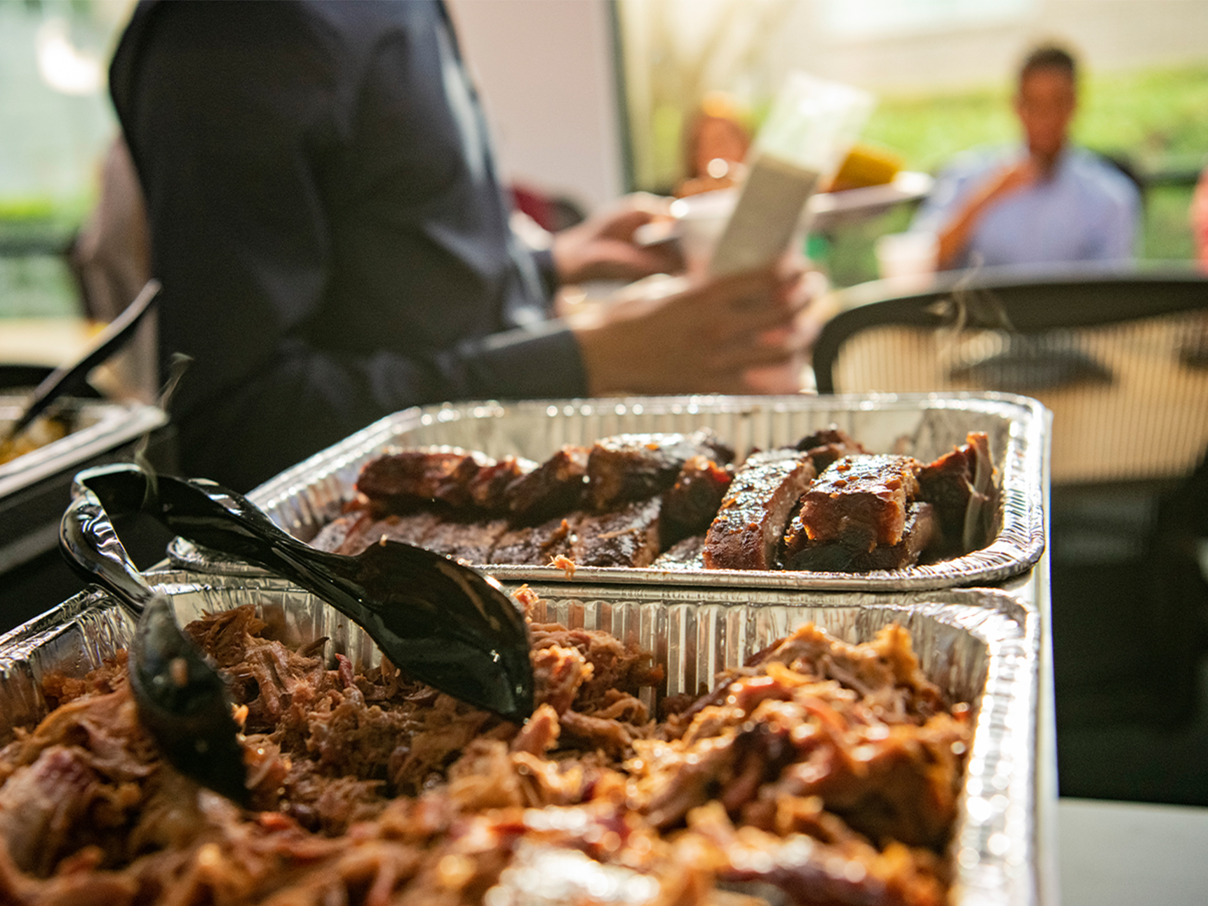 Pans of ribs and pulled pork set out on a serving line at an event catered by Jordan Meats