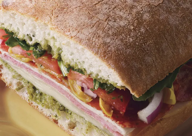 A deli sandwich stacked with meat on a hard roll