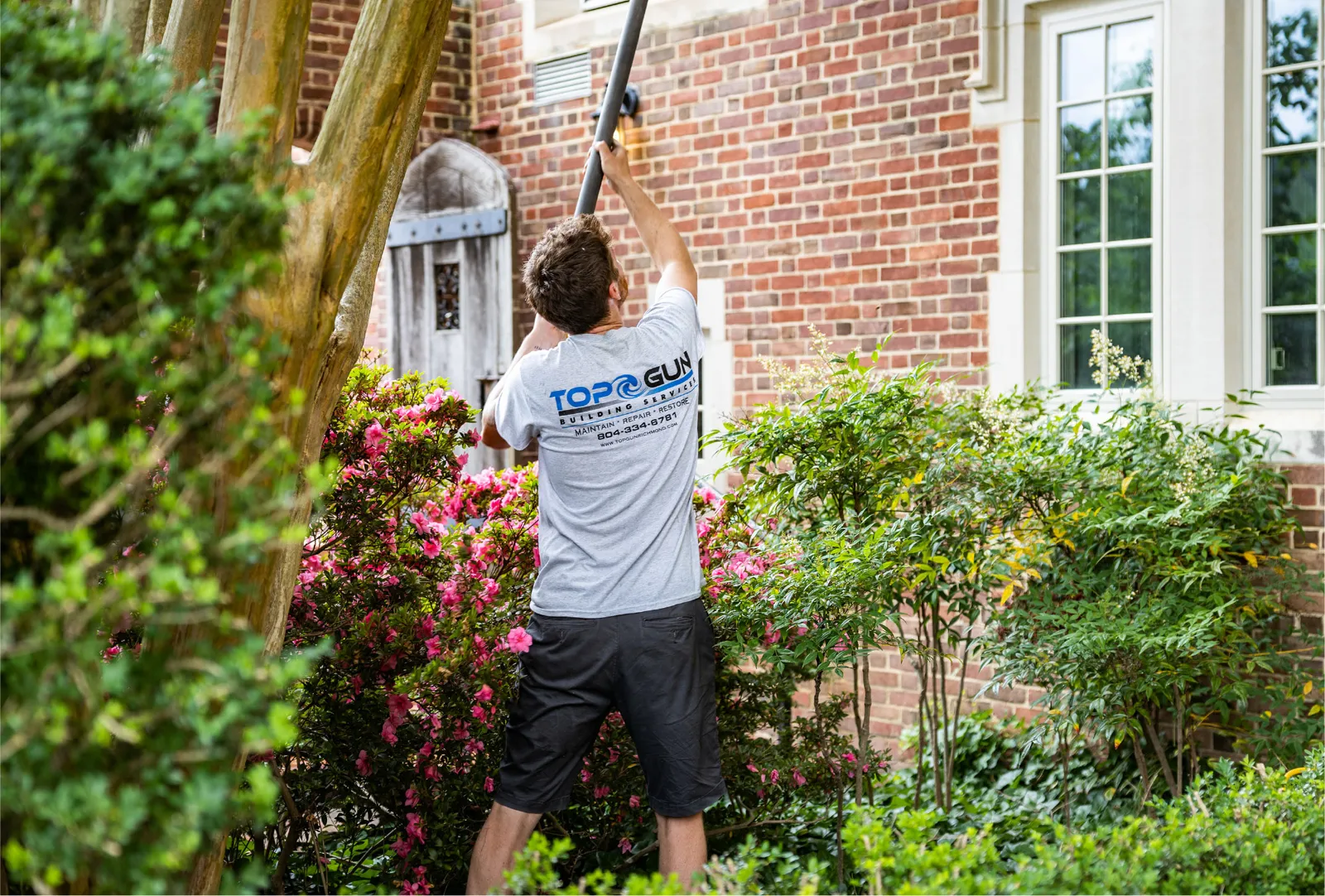 Top Gun technician cleaning a home's upper windows with a water-fed pole