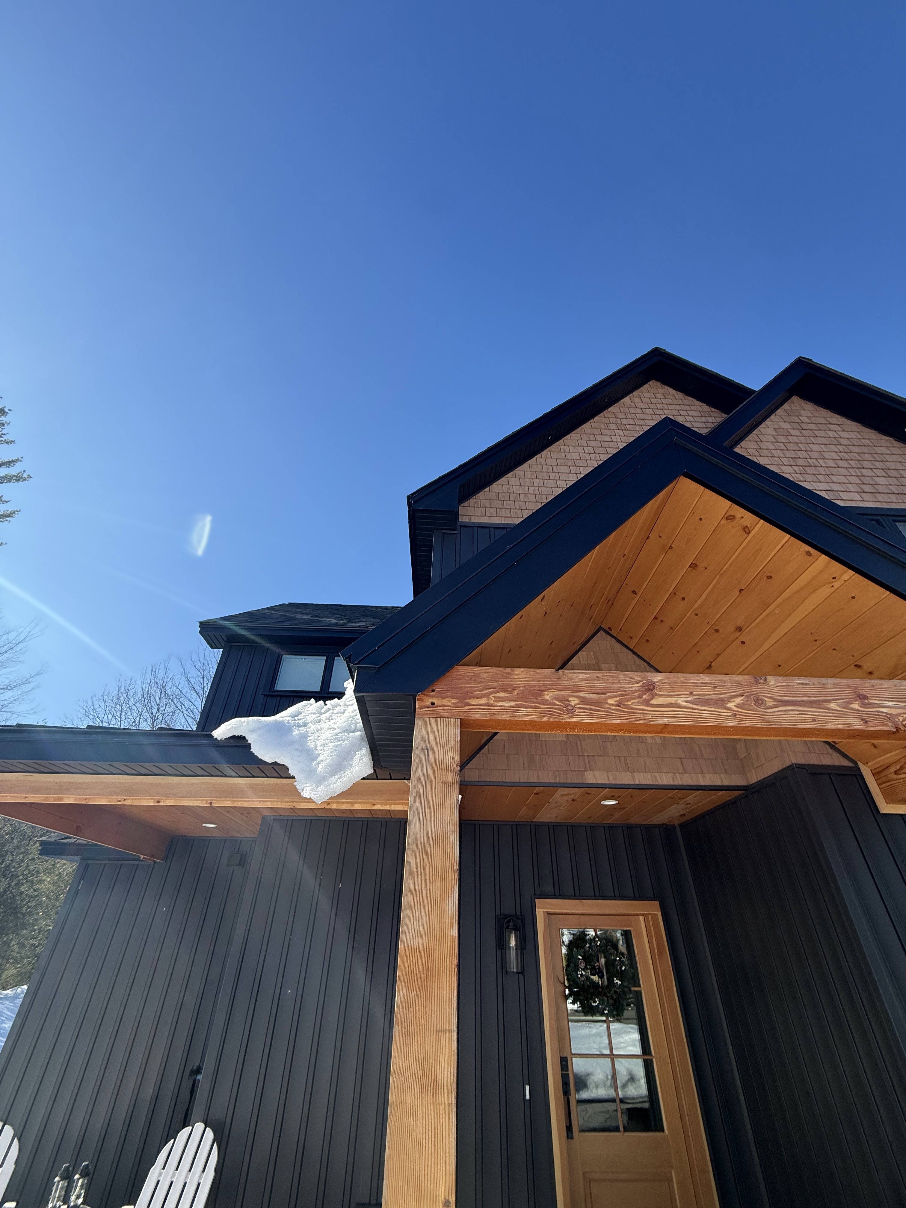 Custom home exterior with black siding, cedar details, and a timber entry